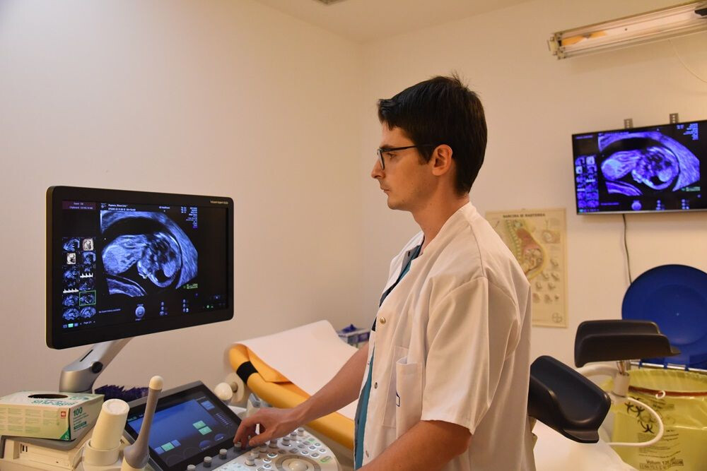 Dr. Cătălin Herghelegiu în fața unui monitor de ecograf, în timpul unei ecografii de sarcină.